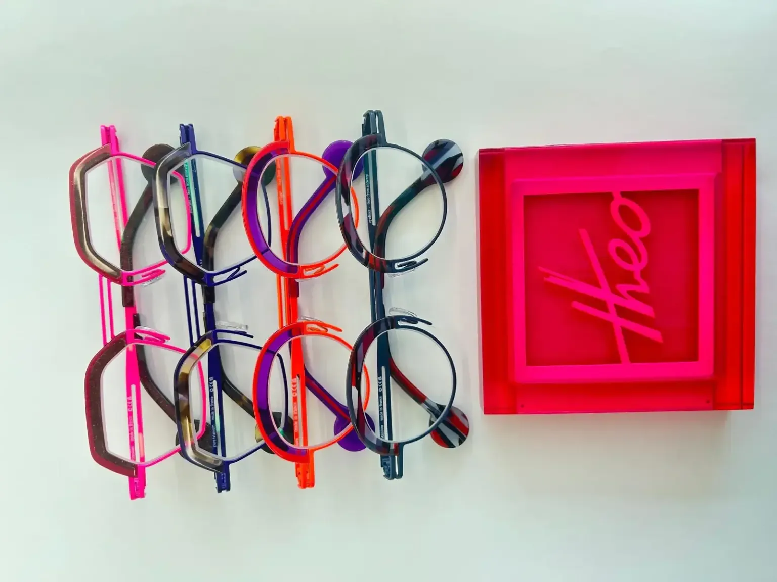 Theo designer glasses beside a pink Theo display sign